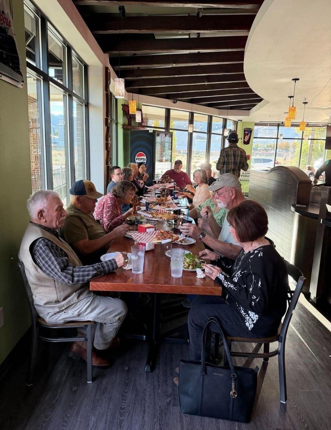 Group enjoying a team lunch at a long table inside Mama Tina's Wood Fired Pizza in Wenatchee